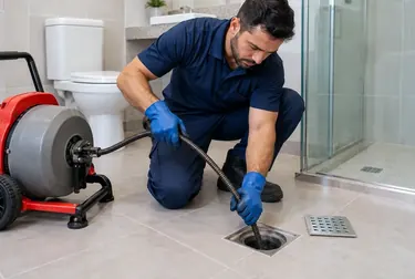 Profissionais realizando desentupimento de ralo em uma residência.